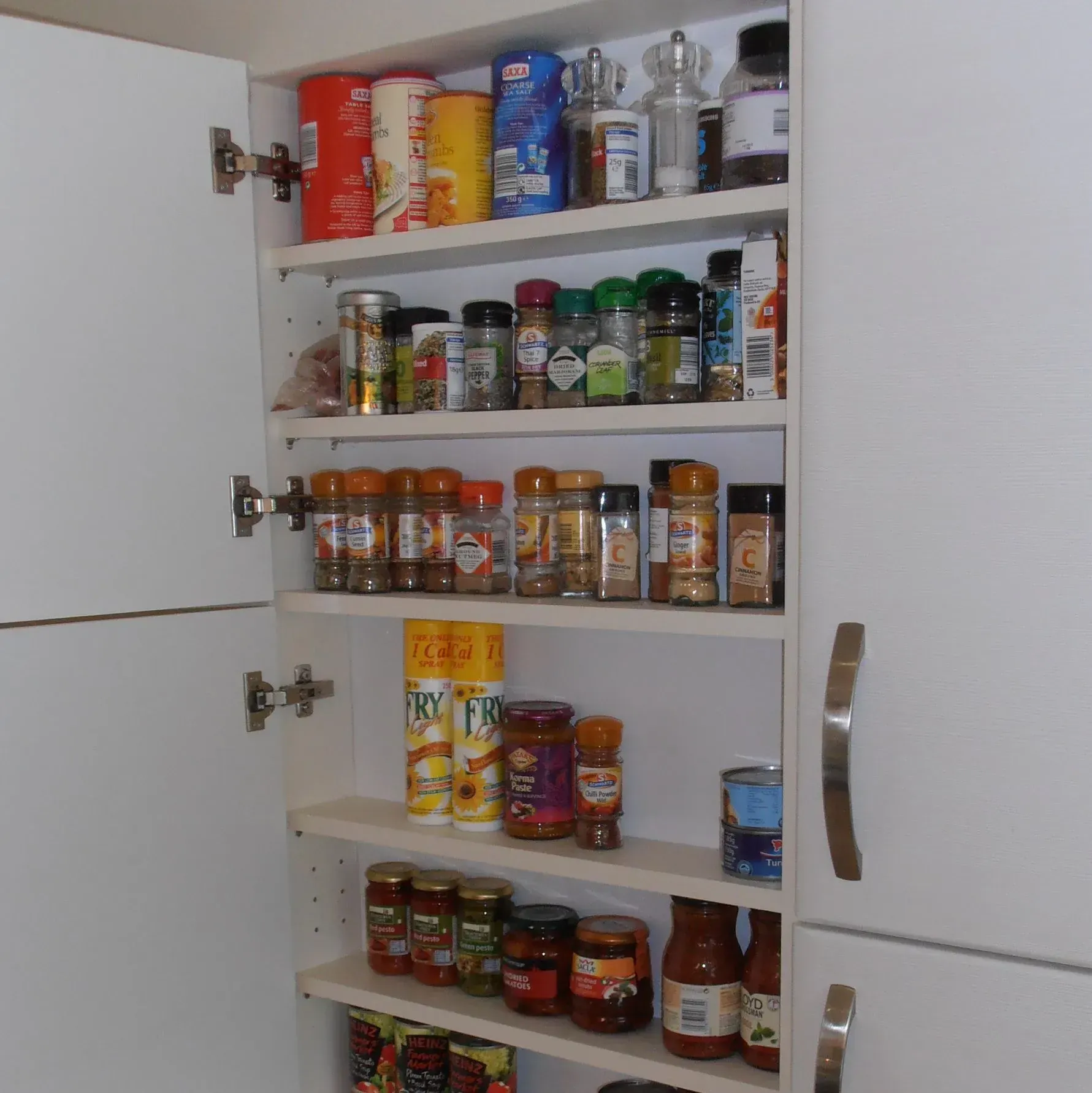 White pantry with shelves holding various spices, jars, and food items.