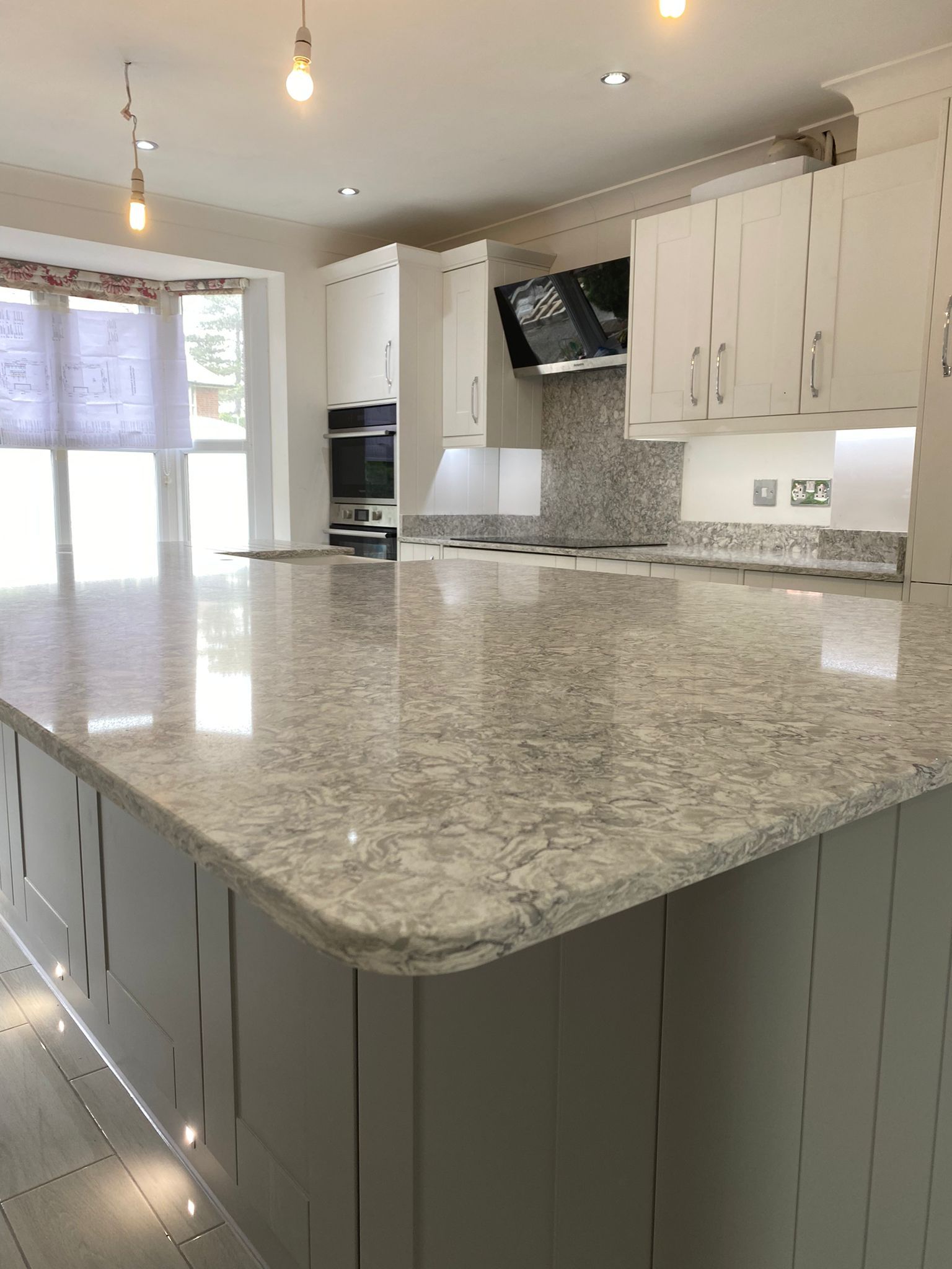 Modern kitchen with a large gray countertop island and white cabinets.