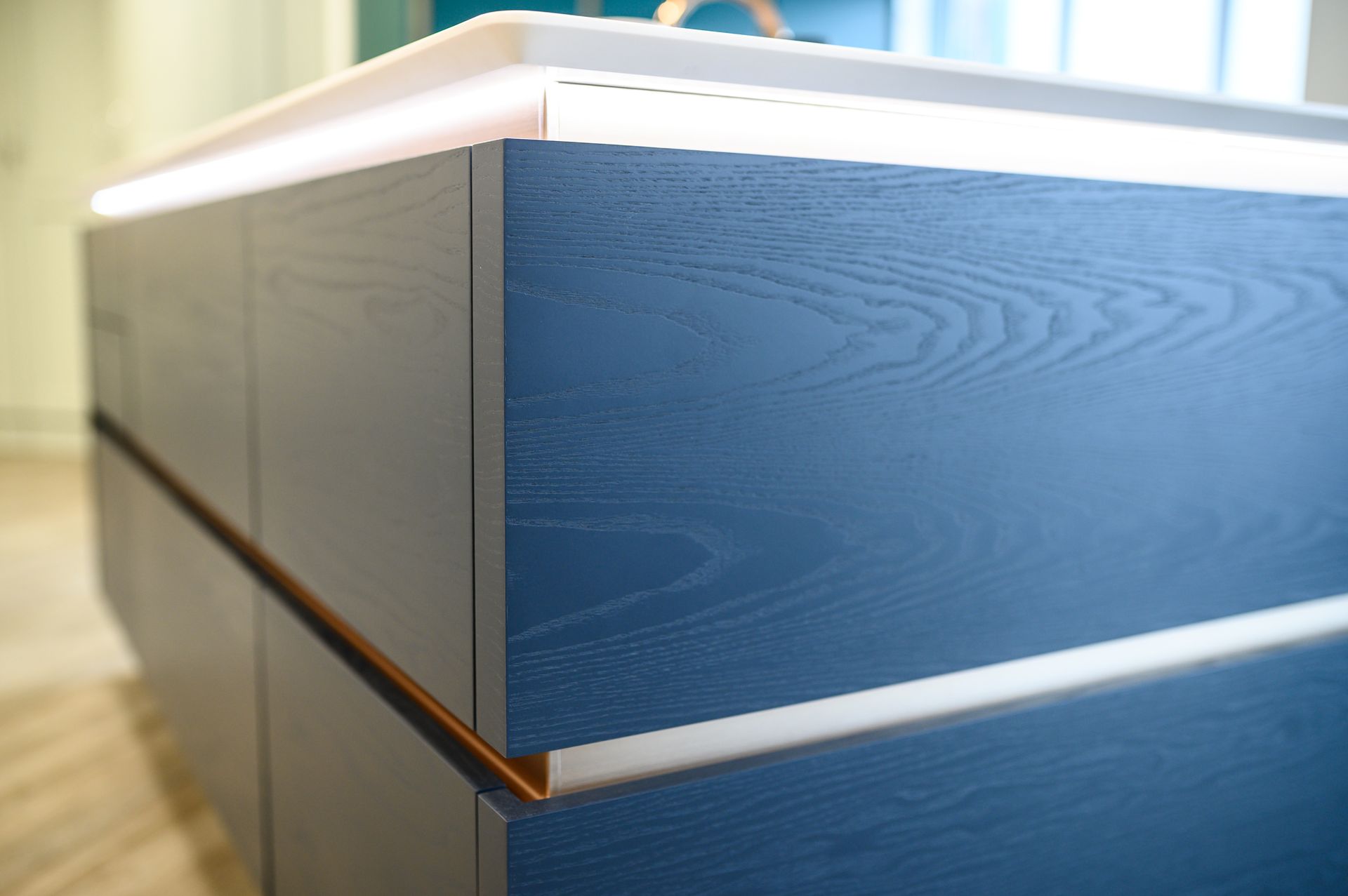 Blue wood-grain kitchen island with copper trim and overhead lighting.