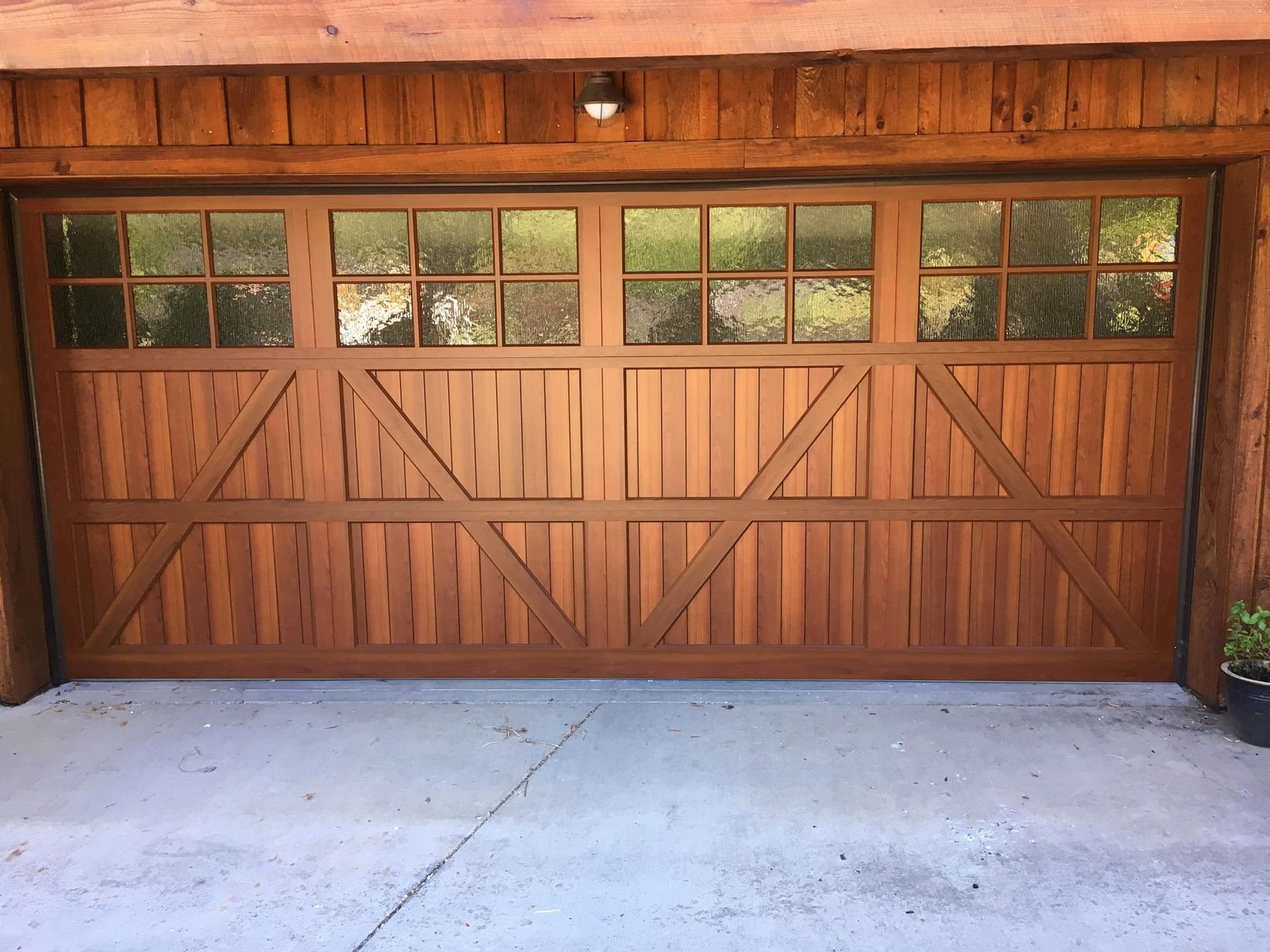 Wooden garage door with windowed top panels, brown wood, on a concrete surface.