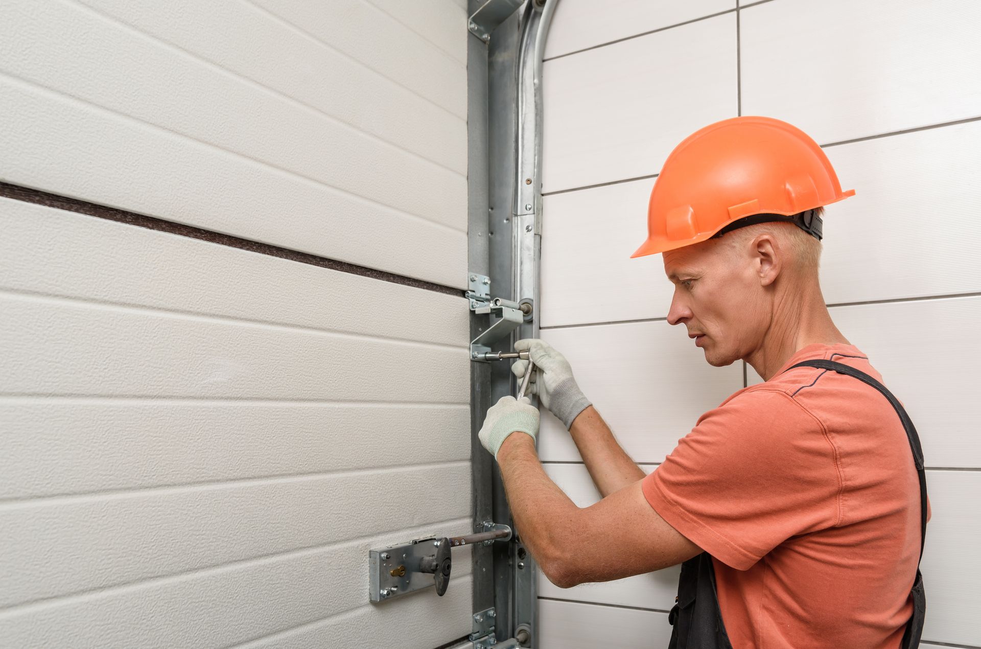 Man in hard hat repairing a garage door.