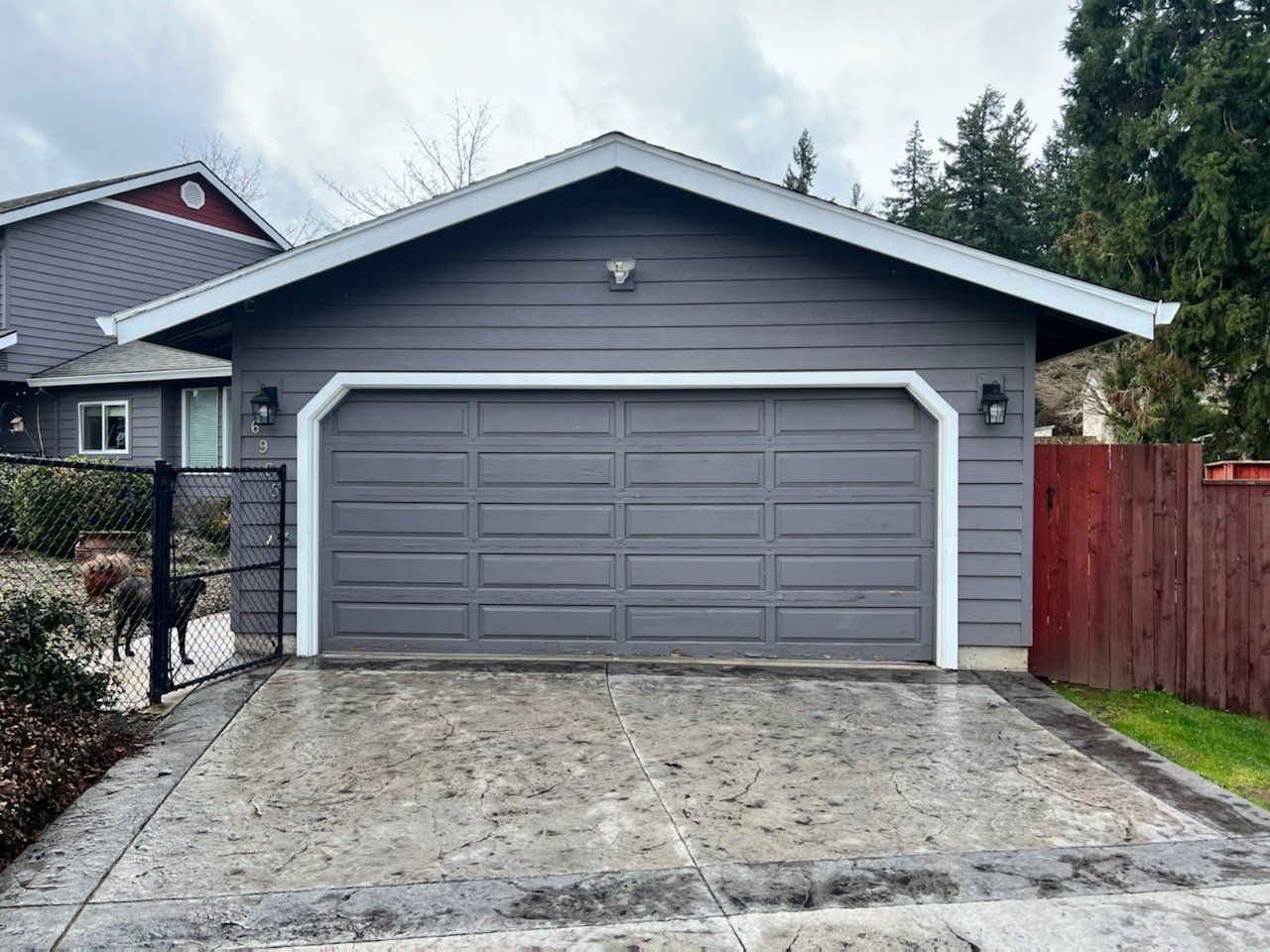 Grey garage with white trim and a concrete driveway.