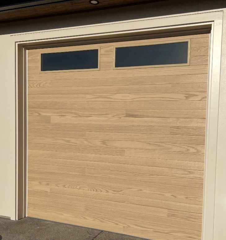 Light wood-grain garage door with two rectangular windows at the top.