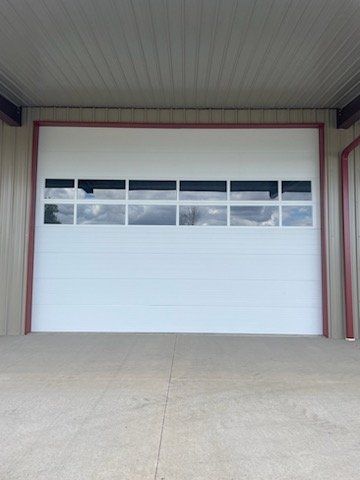 White garage door with windows, set in a building with a concrete floor.