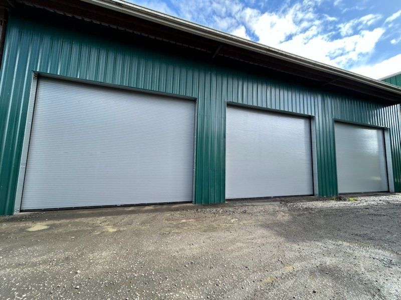 Green metal building with three gray roller doors.