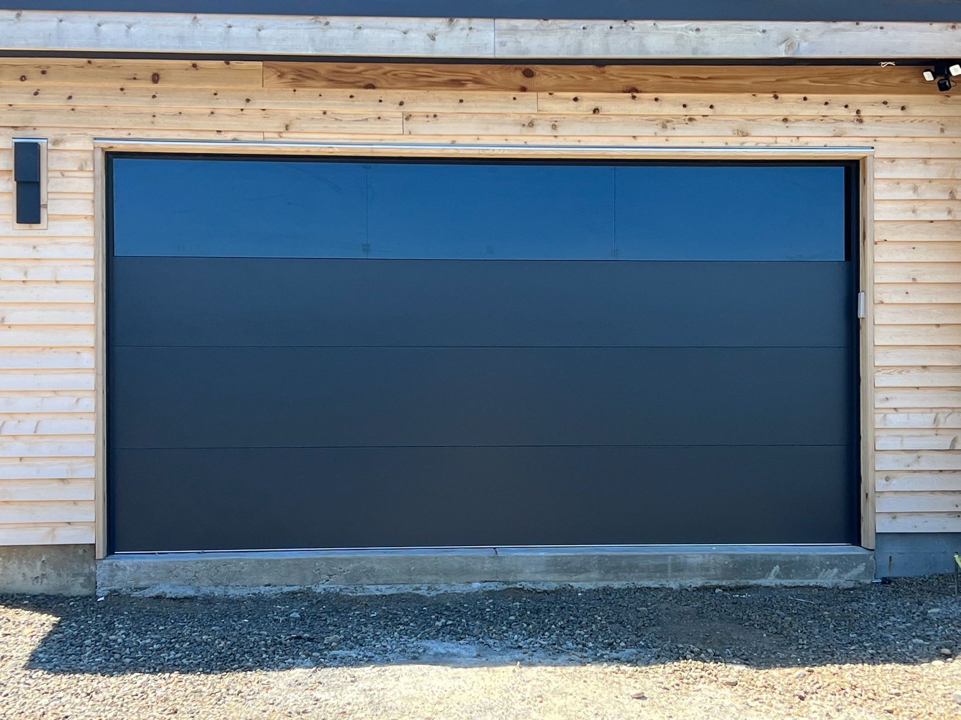 Dark gray garage door in a light wood frame.