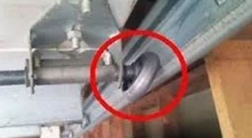 Close-up of a garage door track with a broken roller inside the red circle.