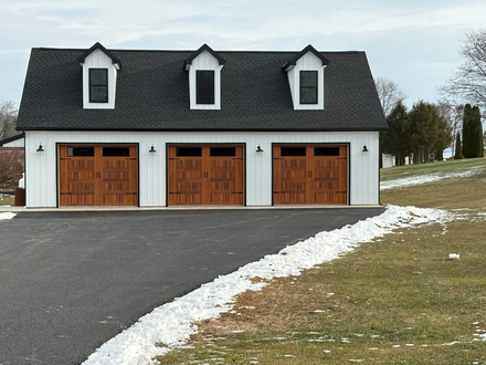 Brown wooden garage door with windows, on a yellow house.