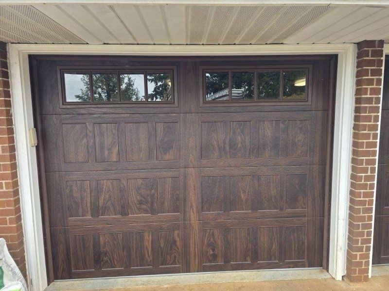 Dark brown garage door with two rectangular glass windows and brick frame.