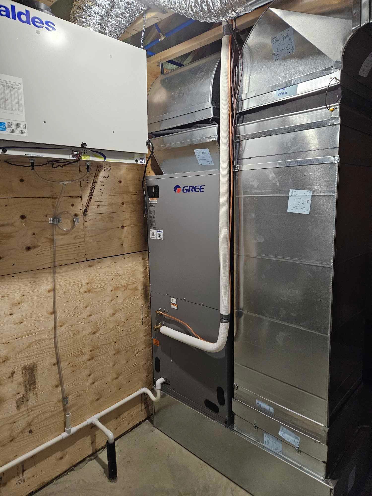 Système de chauffage, ventilation et climatisation (CVC) et conduits d'aération dans un grenier non aménagé avec isolation et charpente apparente.
