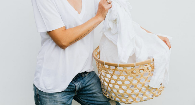 Person holding laundry basket filled with white laundry