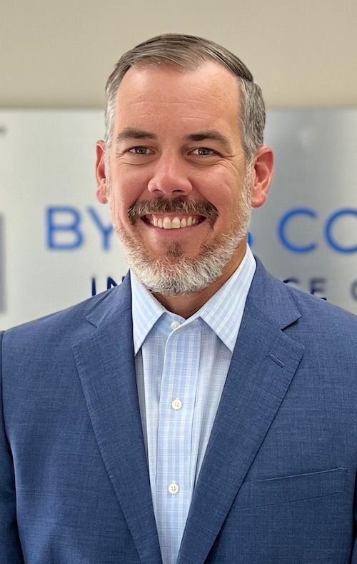 A man with a beard is wearing a blue suit and smiling.