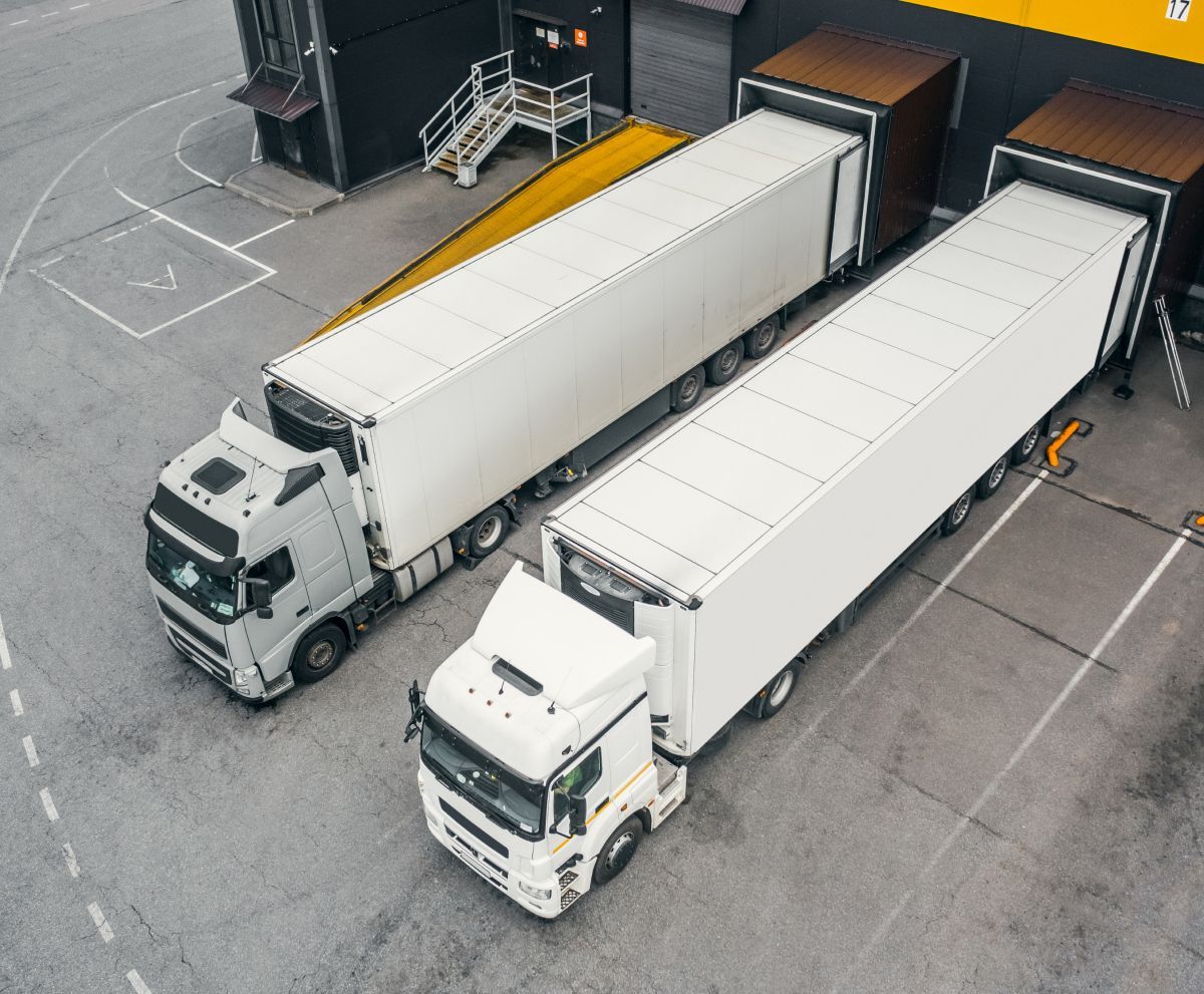 Two white semi trucks are parked next to each other in a parking lot.