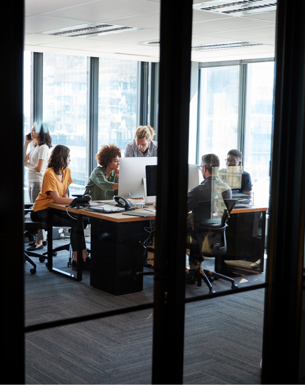 A group of people are sitting at desks in an office looking at computers.