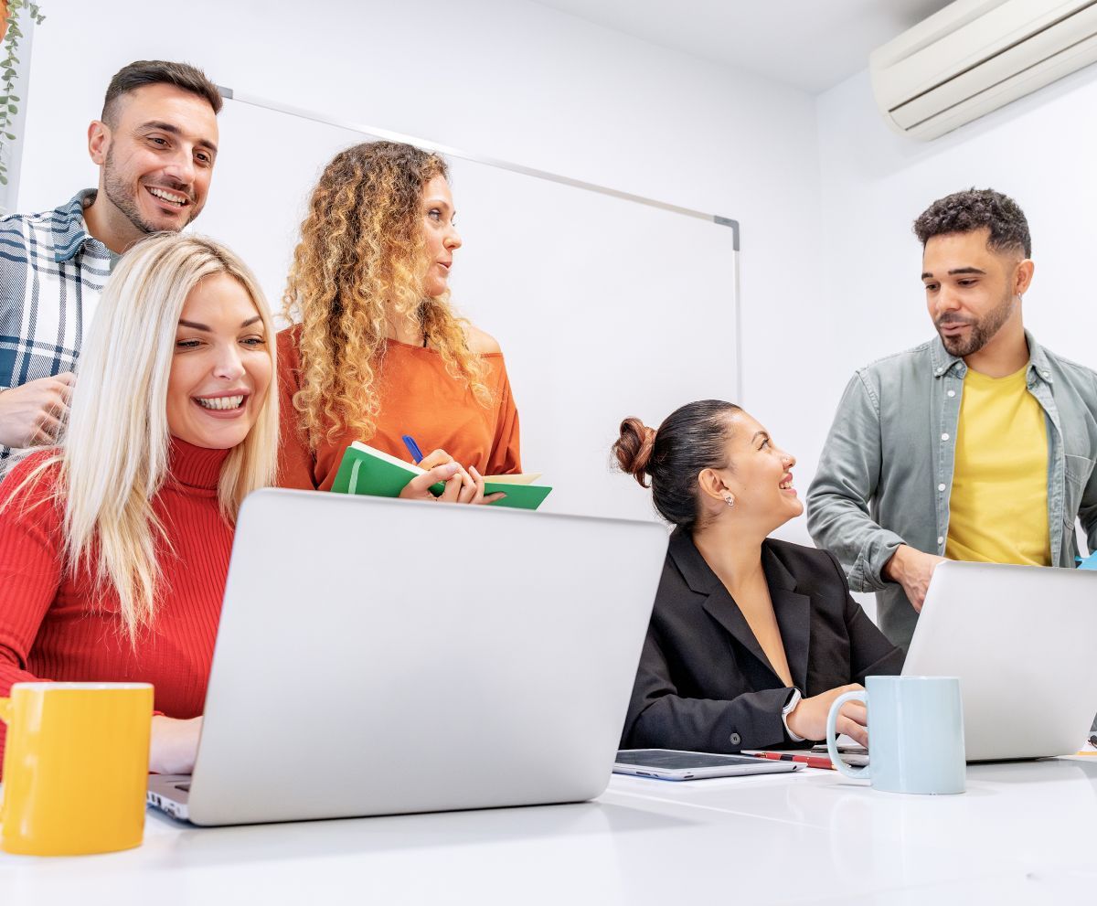 A group of people are sitting at a table with laptops.