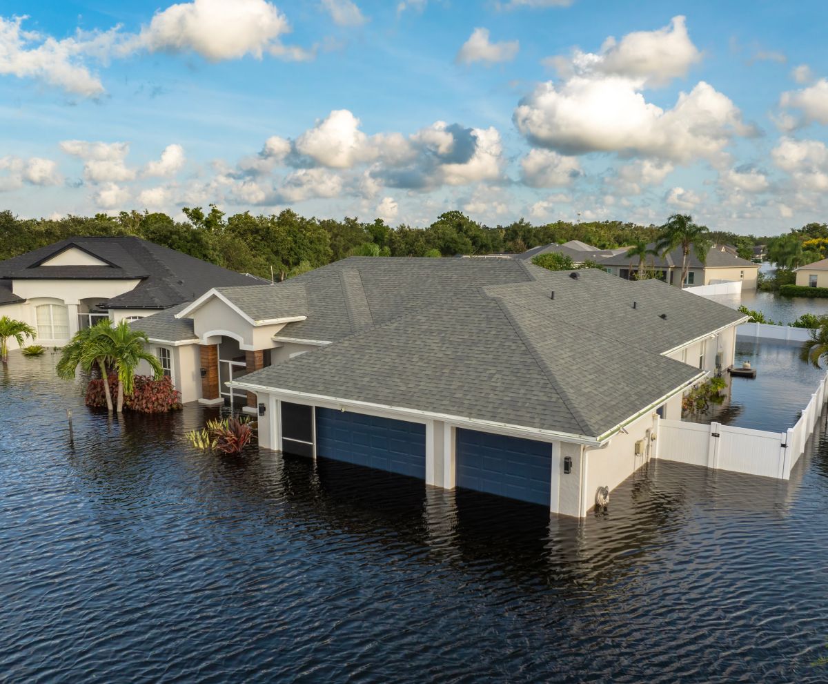 An aerial view of a flooded house in a residential area.