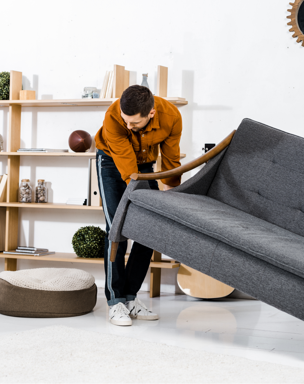 A man is moving a couch in a living room.