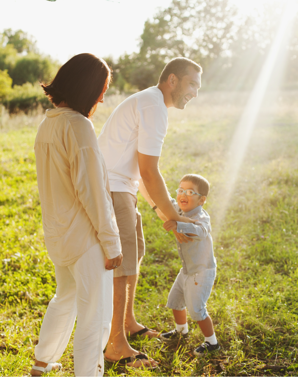 A family is standing in a grassy field holding hands.