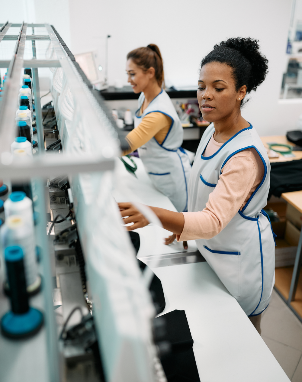 Two women are working on a machine in a factory.