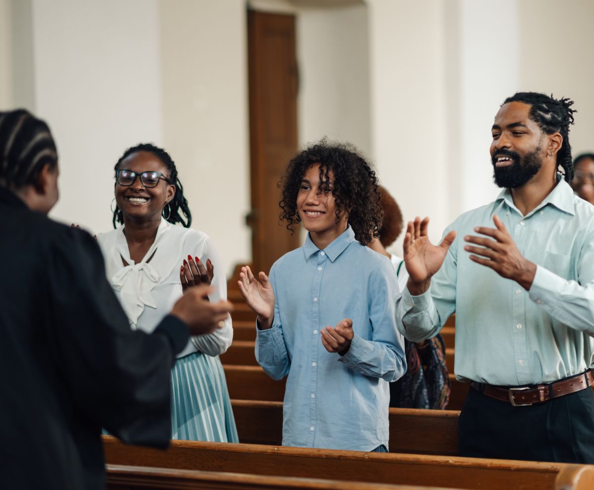 A group of people are standing in a church with their hands in the air.
