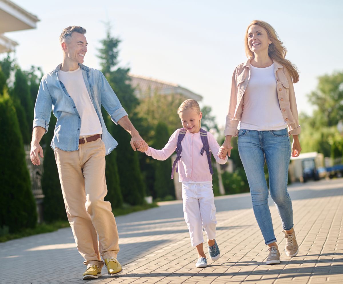A family is walking down a sidewalk holding hands.
