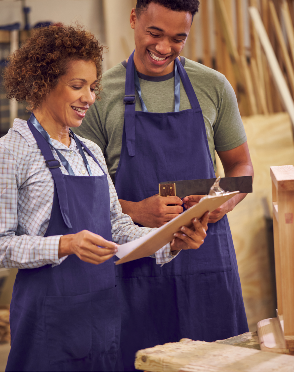 A man and a woman are looking at a clipboard in a workshop.
