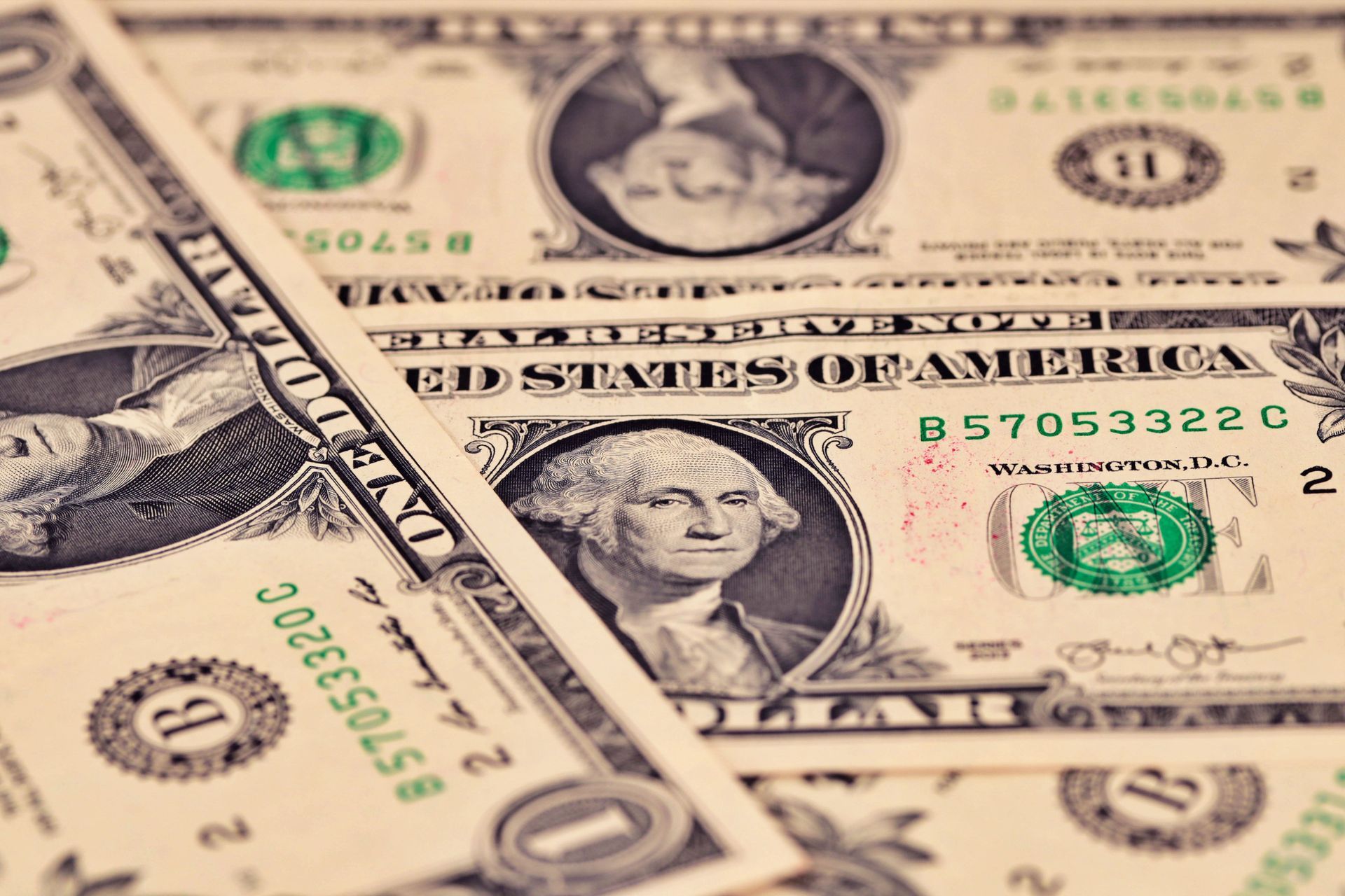 Close-up of overlapping US one-dollar bills with George Washington portrait and green seals.