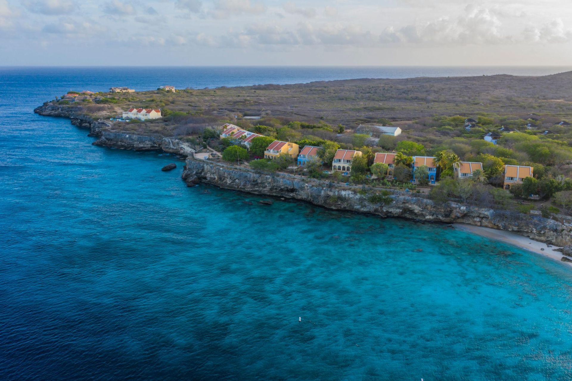 Een dorpje op een klif aan de kust van Curacao, boven een turquoise zee