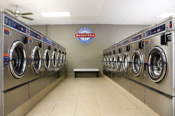 A laundromat filled with lots of washing machines and a bench.