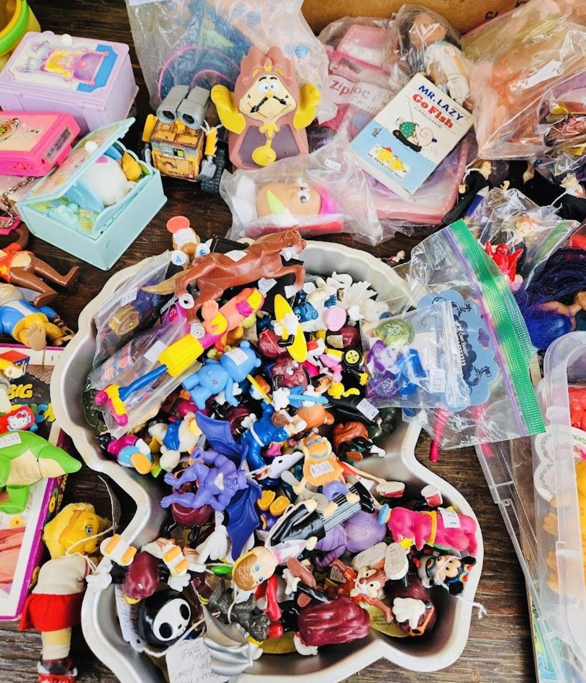 Assorted colorful toys and figurines piled in plastic bins and bags