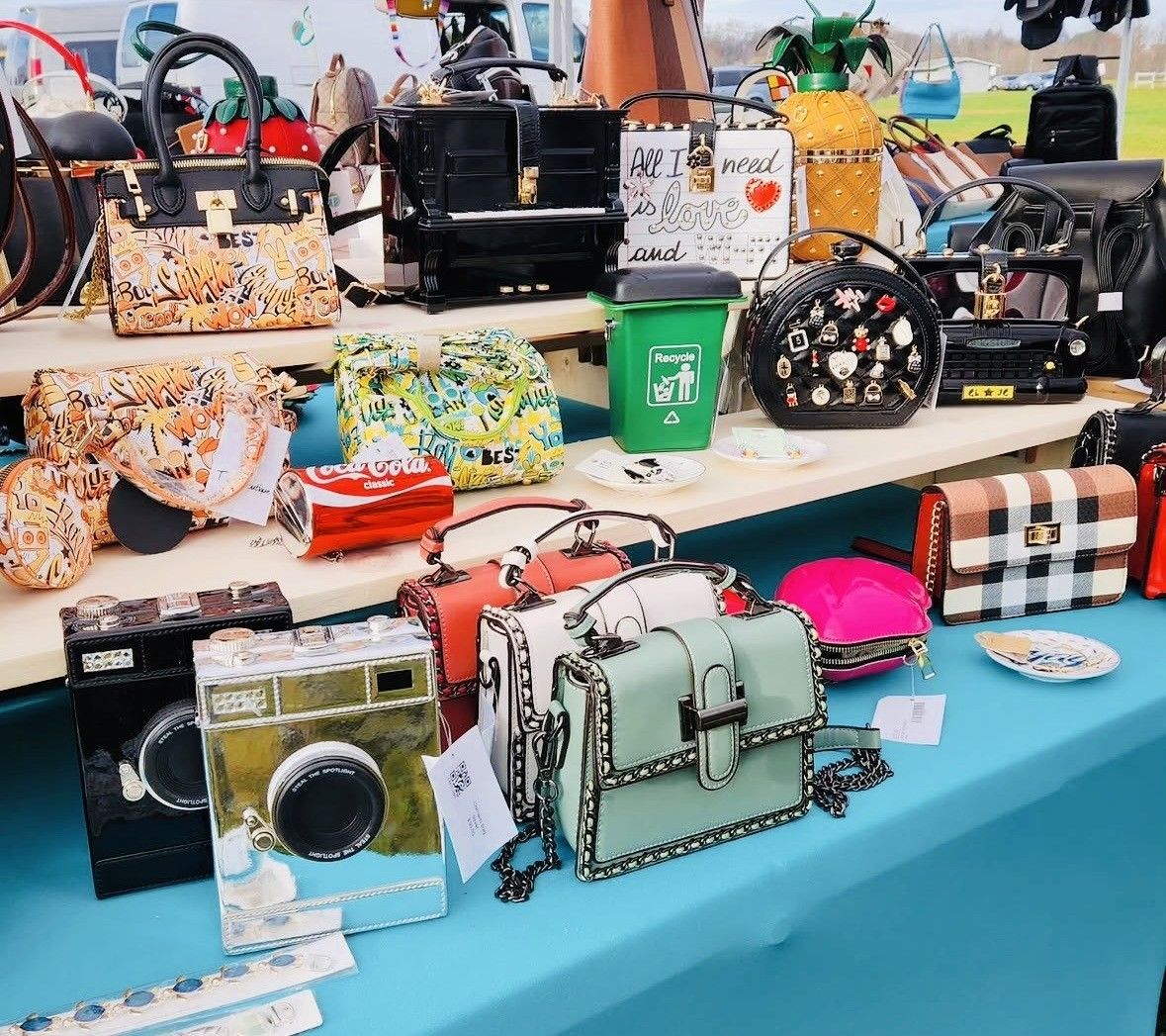 Assorted colorful handbags and small accessories displayed on a market table with a turquoise cloth
