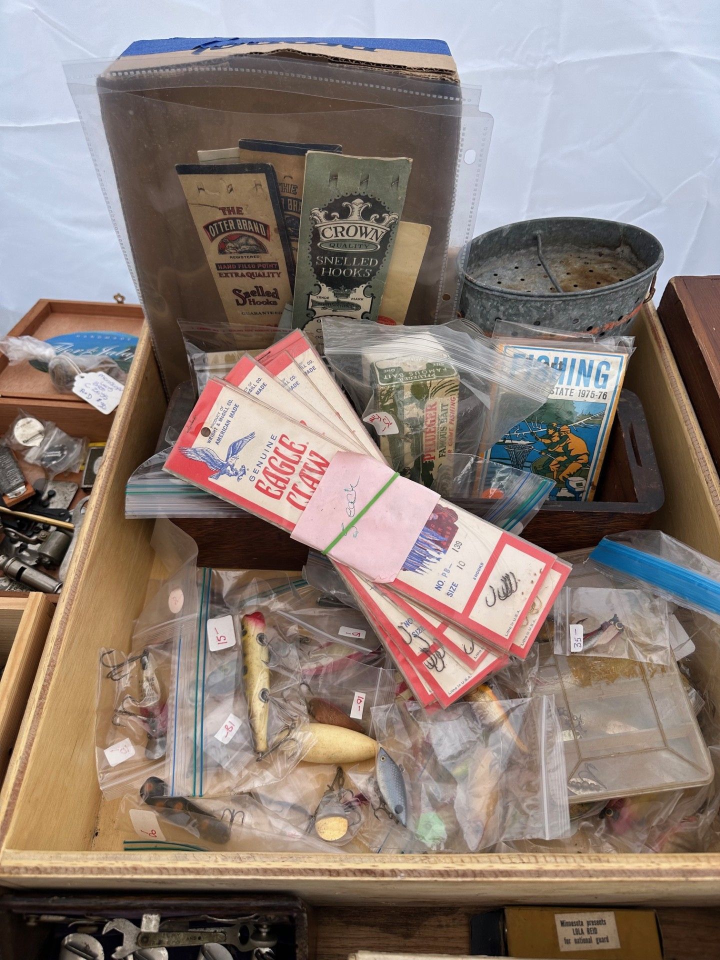 Cardboard box of assorted vintage collectible and craft items, with papers, tins, and small trinkets.