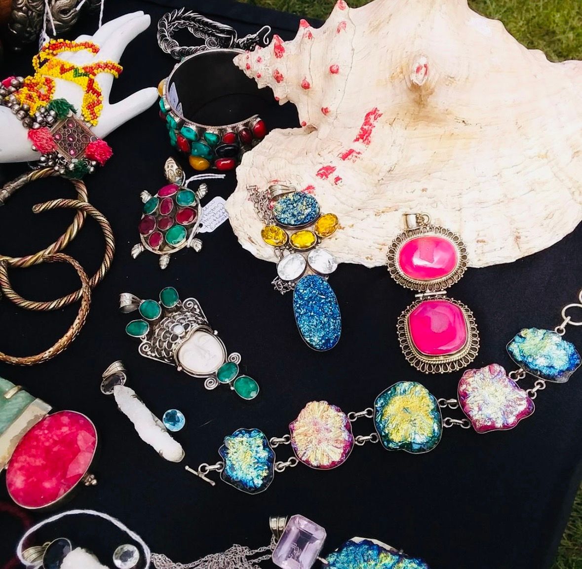Assorted colorful jewelry on black velvet with a white shell in the background