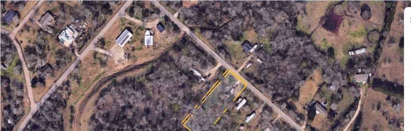 Aerial view of a rural area with roads, houses, and trees. Some parcels are outlined in yellow.