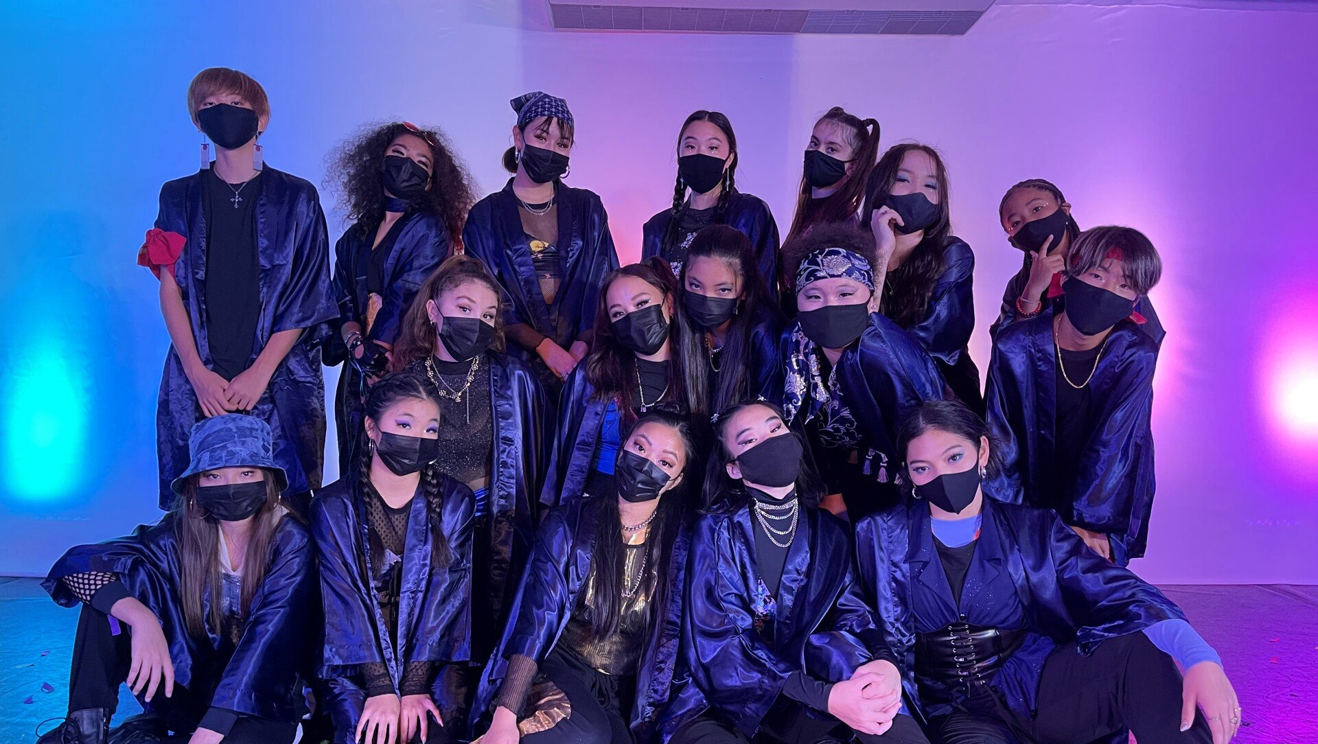 A group of young people wearing face masks are posing for a picture.