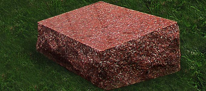A red brick is sitting on top of a lush green field.