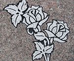 Etched white roses on a gray stone surface.