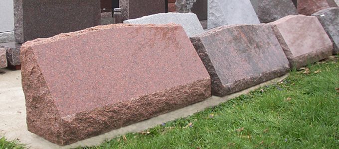 A row of gravestones is lined up in a grassy area.