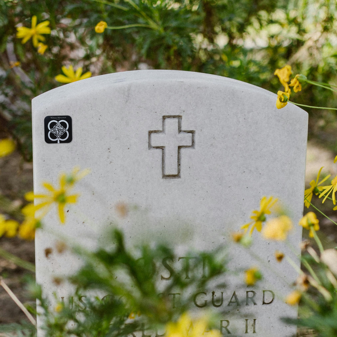 Headstone with cross and emblem surrounded by yellow flowers.