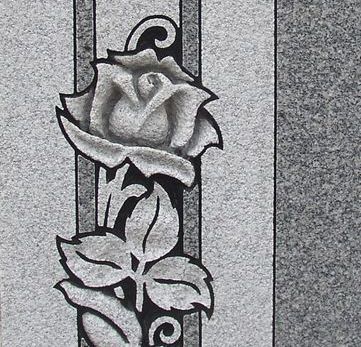 Gray granite headstone with a carved rose design.