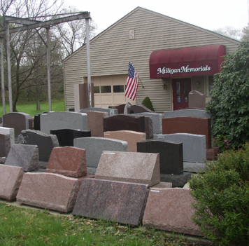 Milligan Memorials: Gravestones on display outside a shop with an American flag.