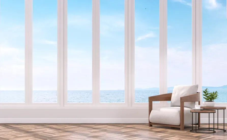 A living room with a chair and a table with a view of the ocean.