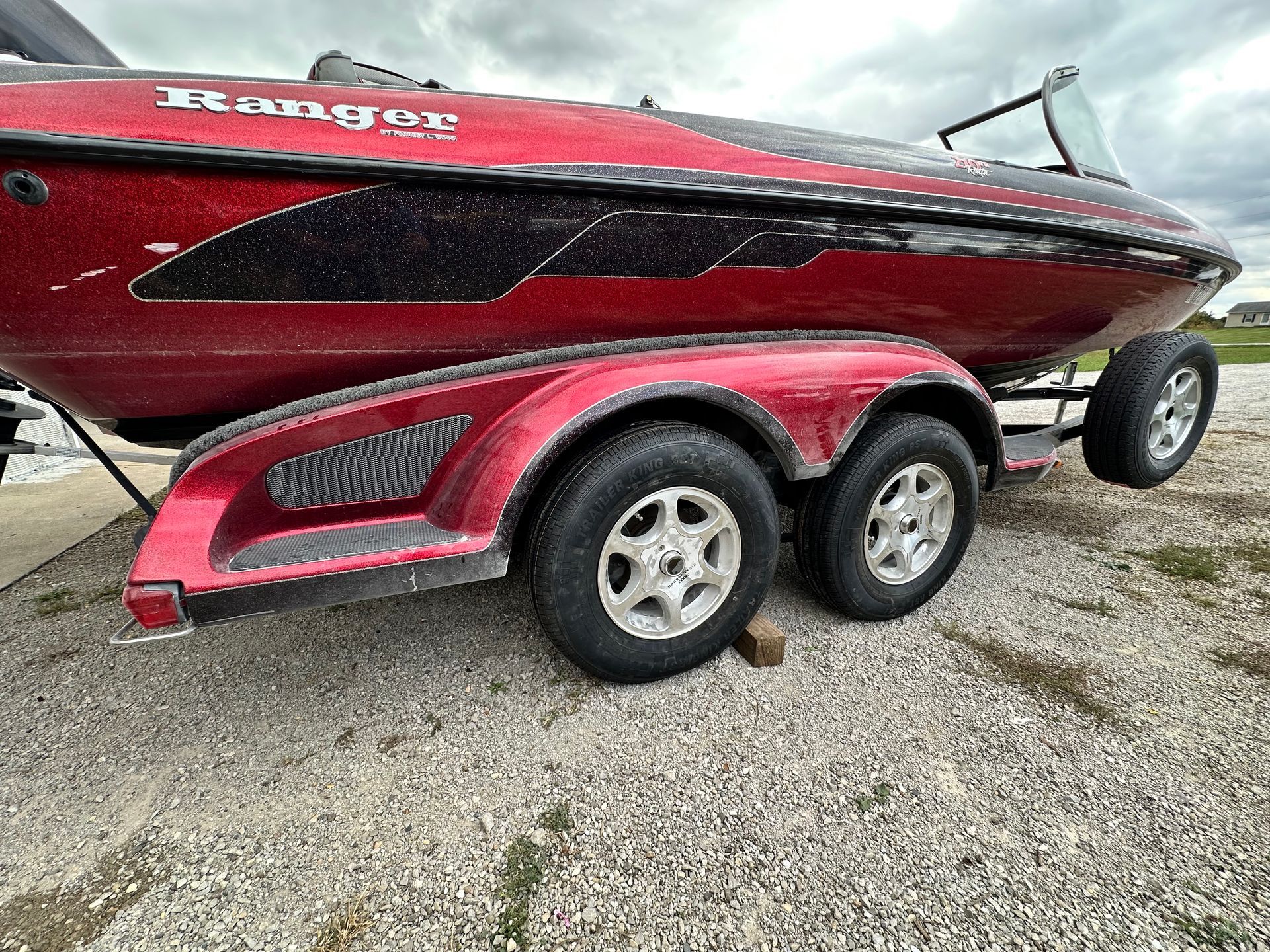 Red Ranger boat on a trailer with two tires, on a gravel surface. | Midwest Tire & Service LLC