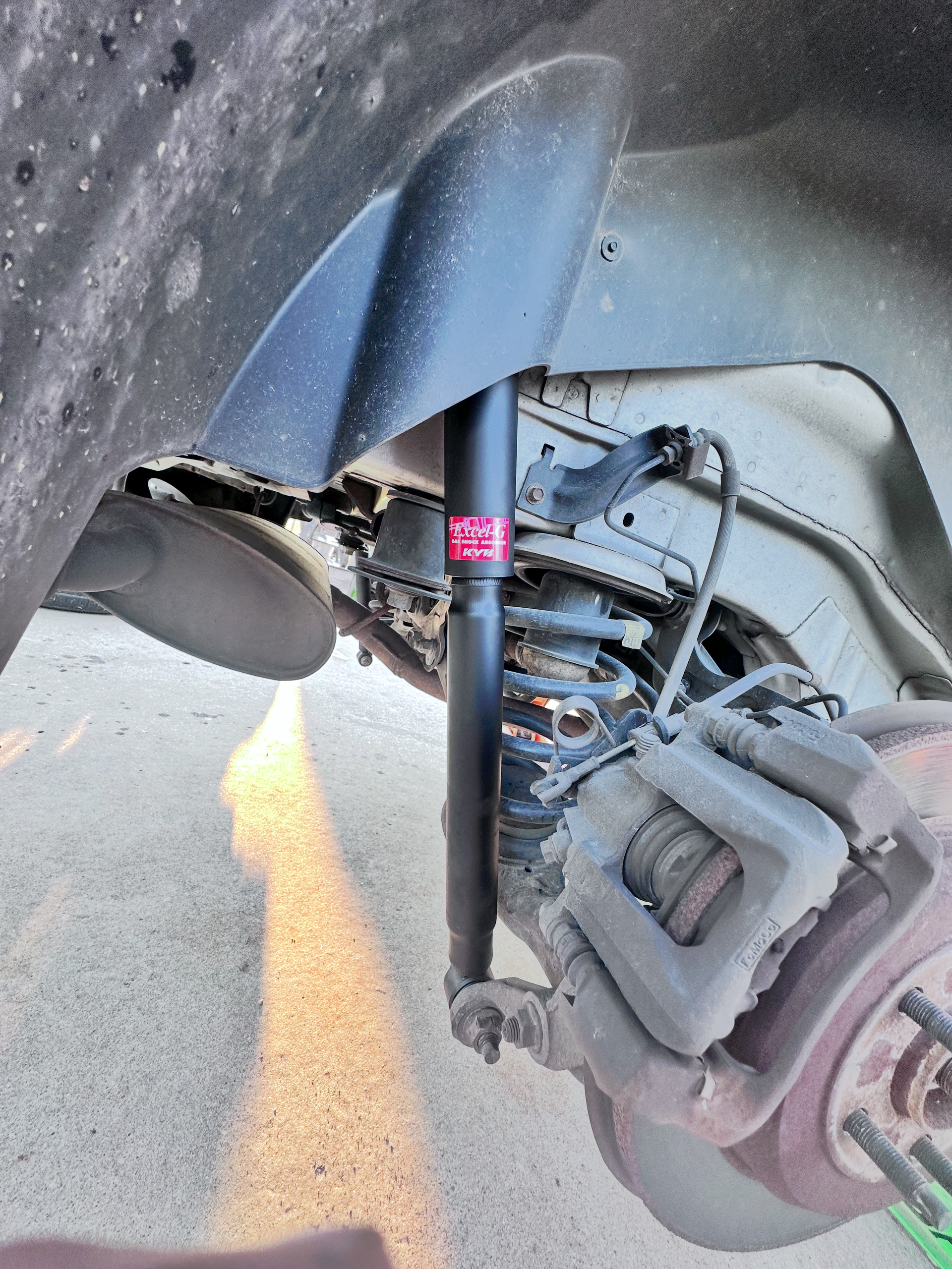 Car's rear suspension, shock absorber, and brake system visible from the side. | Midwest Tire & Service LLC