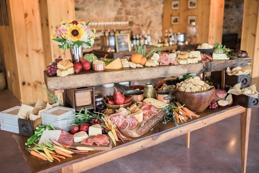 Charcuterie board on a rustic table, with cheese, meats, fruit, and flowers in a wooden setting for a Maryland Wedding