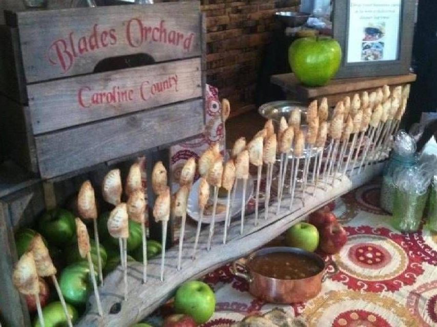 Apple orchard display with caramel apples on sticks, green apples, and a rustic wooden crate.