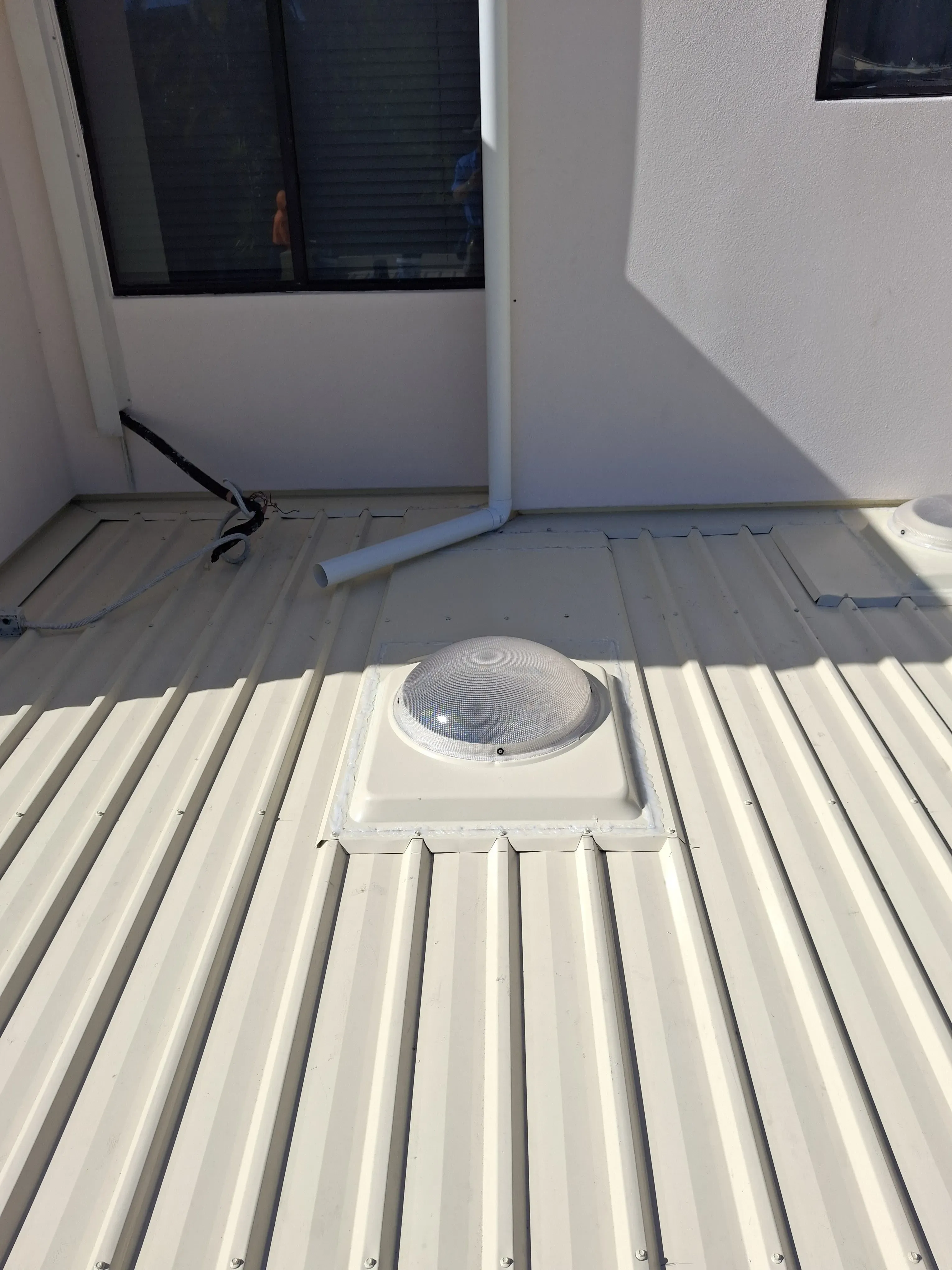White wall-mounted light fixture with clear, textured dome. Next to a textured gray wall and white paneling.