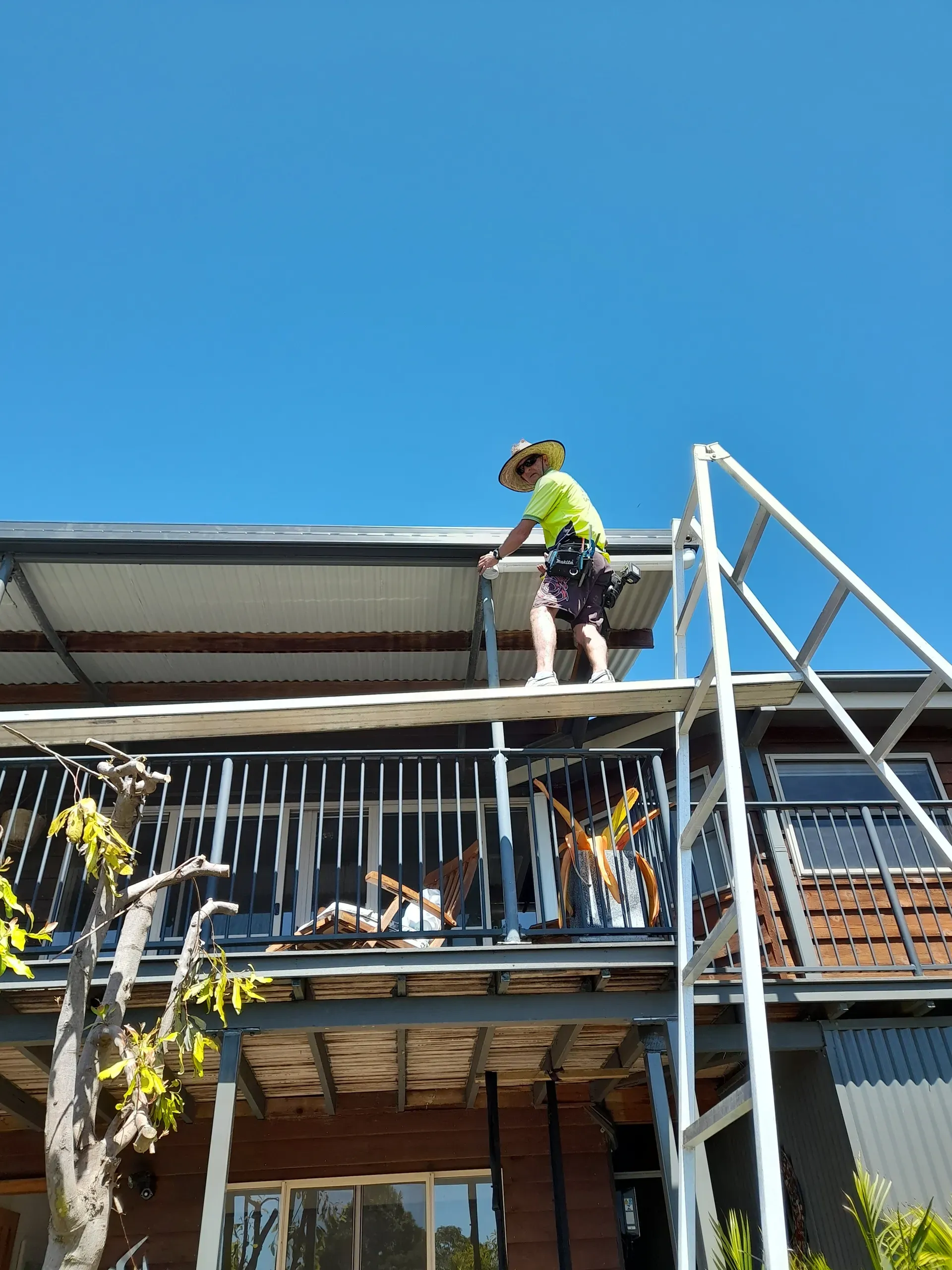 Person on a scaffold working on the roof of a house on a sunny day.
