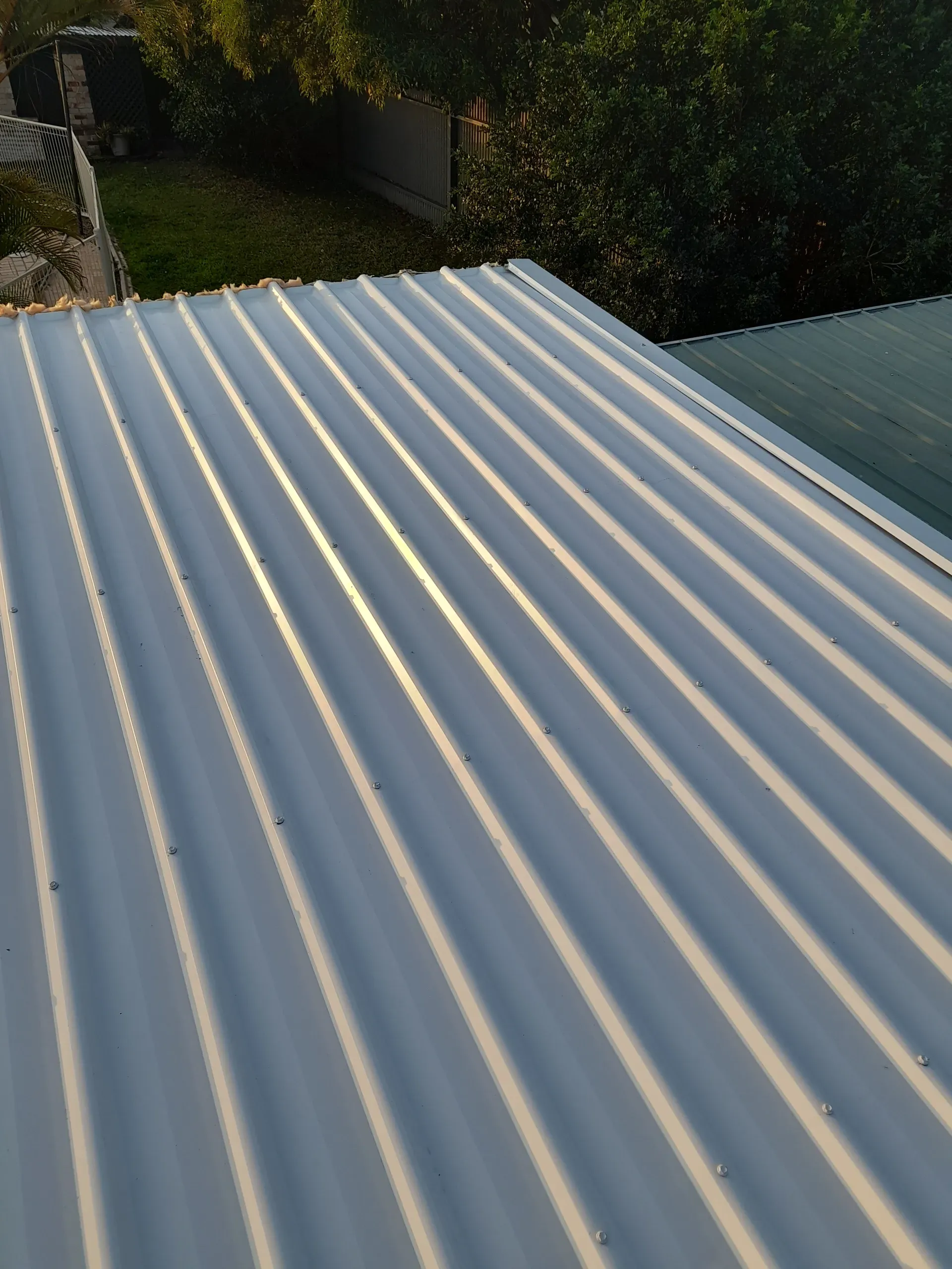 White corrugated metal roof with sunlight creating shadows.