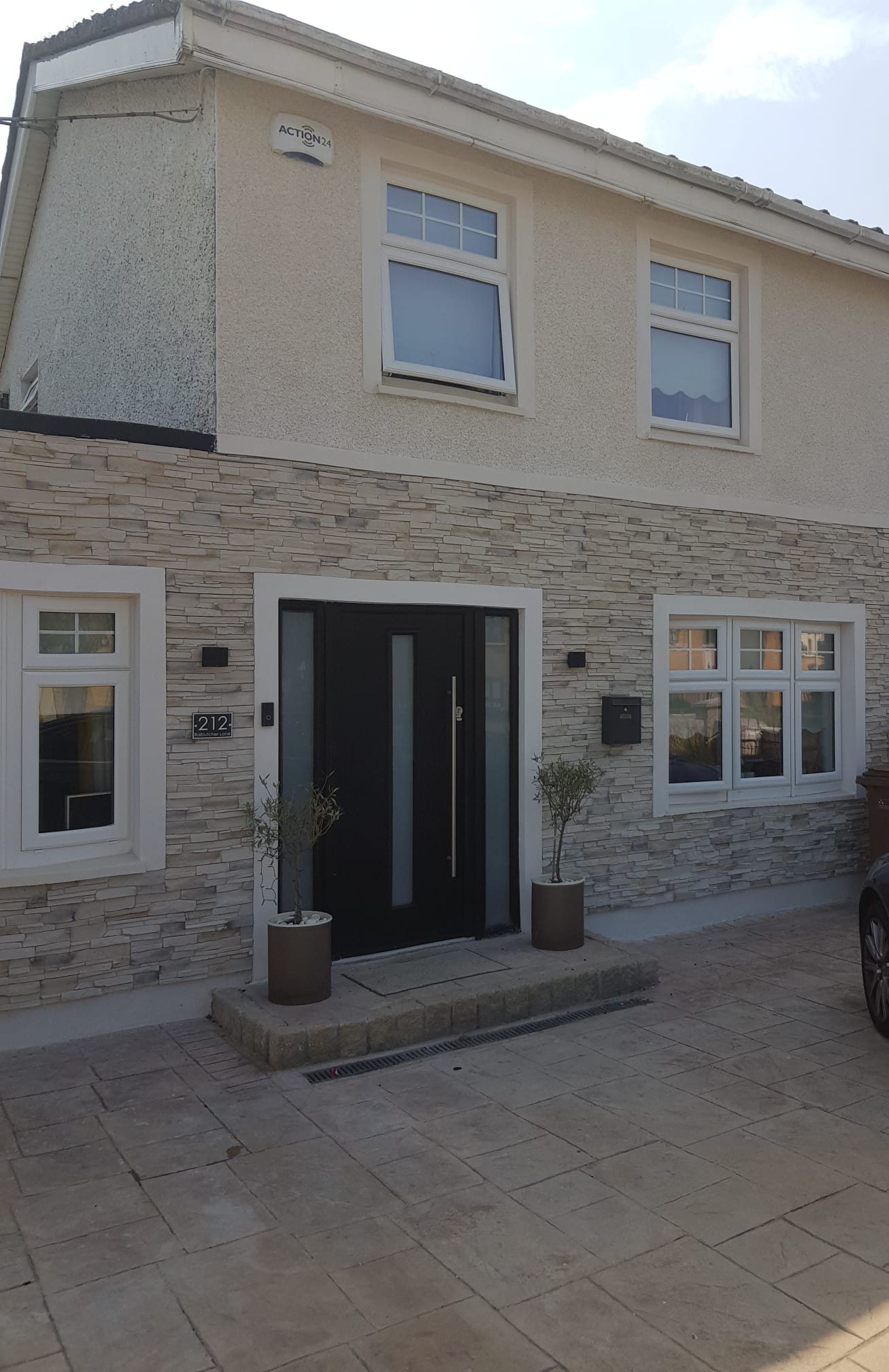 A house with a black door and a car parked in front of it.